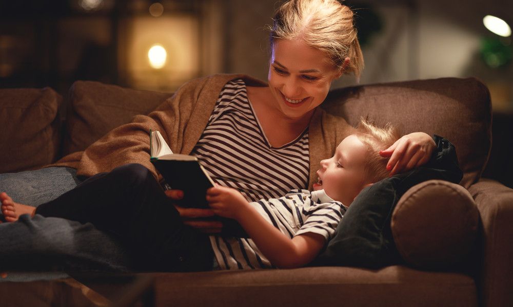 Mutter und Kind liegen auf dem Sofa und lesen ein Buch