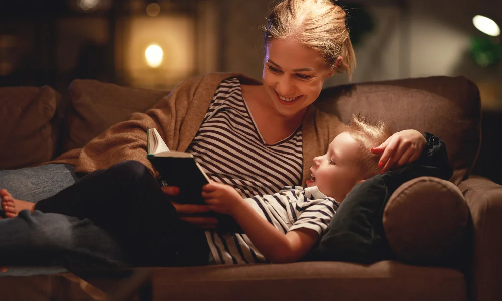 Mutter und Kind liegen auf dem Sofa und lesen ein Buch