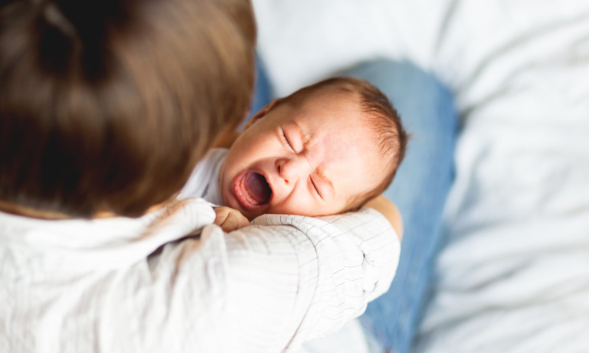 Vater tröstet Baby im Arm.