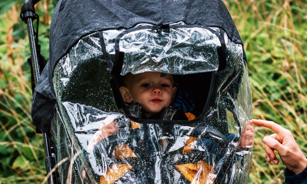 Kleiner Junge wird im Buggy vor dem Regen geschützt