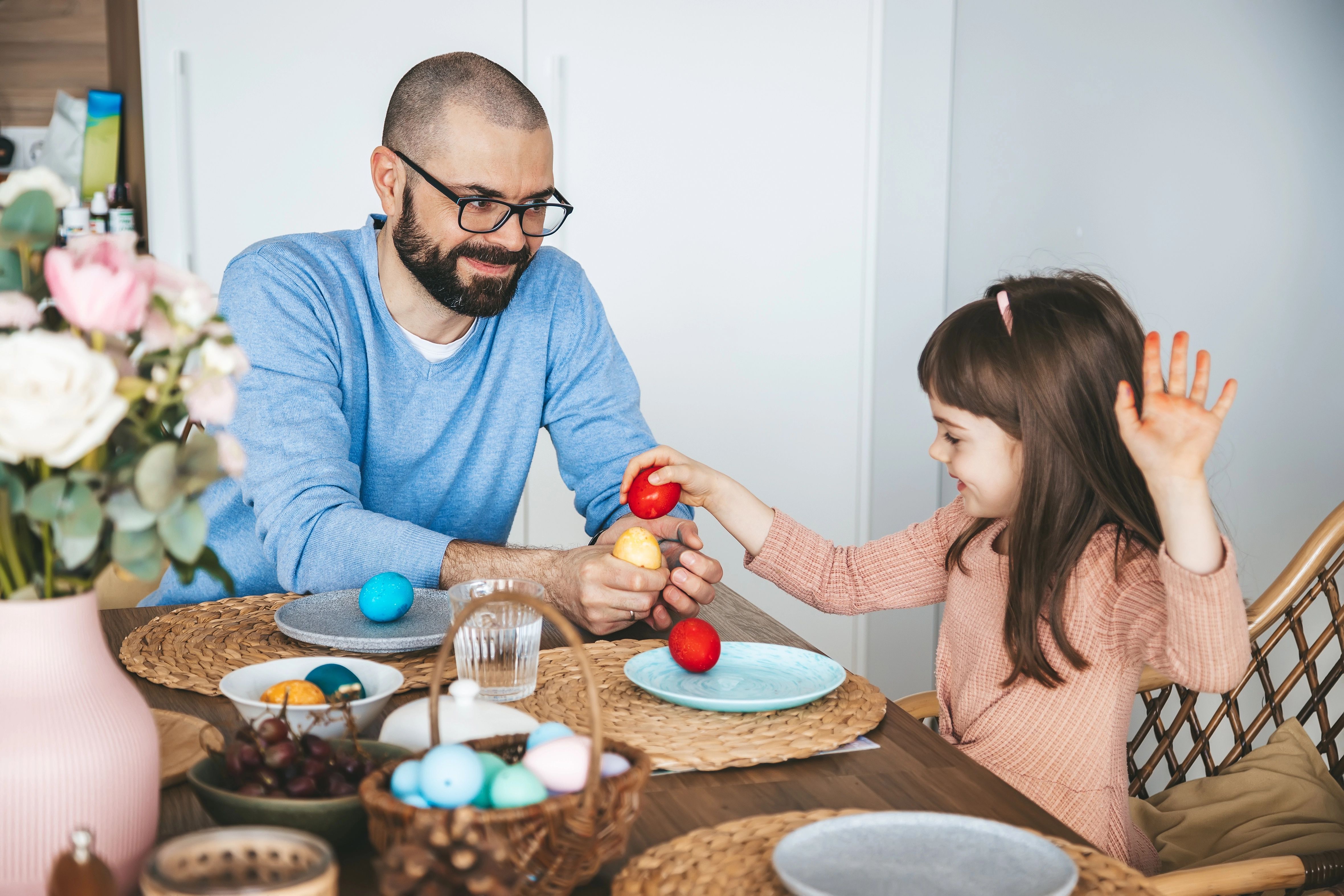 Familie sitzt am Tisch und schlagen ihre Frühstückseier als Tradition gegeneinander.