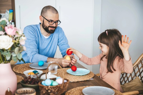Familie sitzt am Tisch und schlagen ihre Frühstückseier als Tradition gegeneinander.