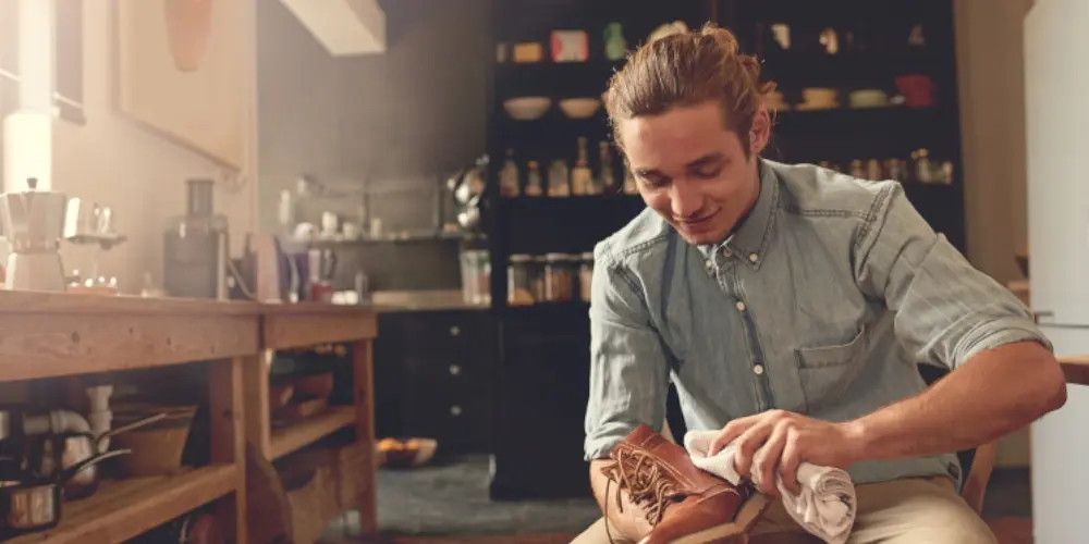 Junger Mann putzt Lederschuhe