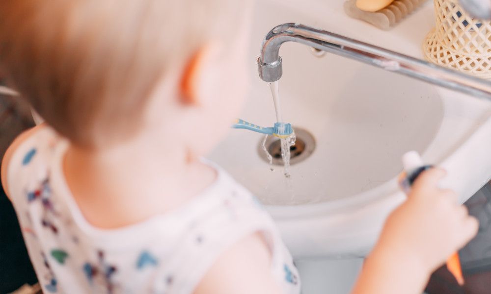 Kleines Kind putzt sich am Waschbecken Zähne.