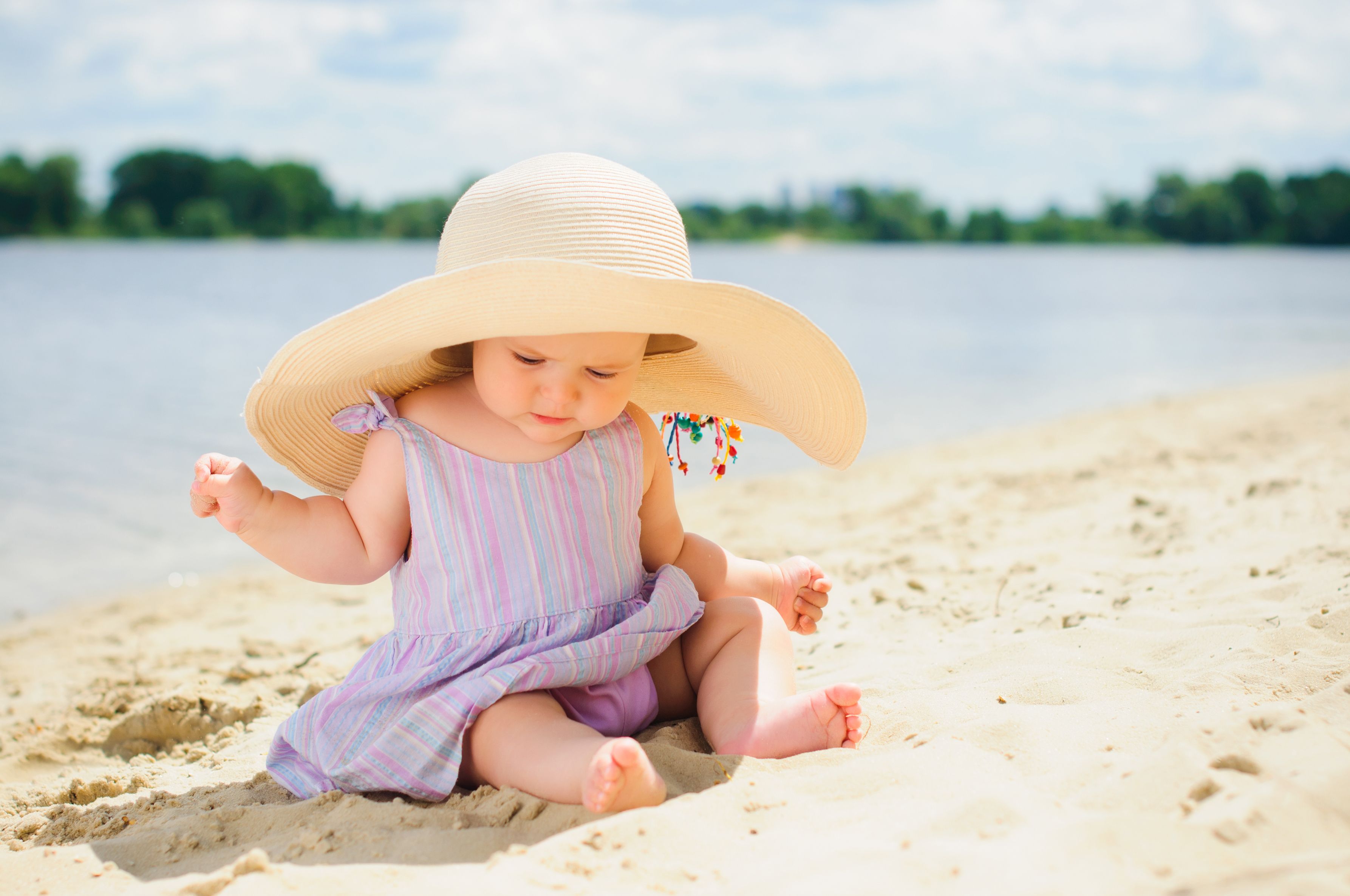 Kleine süße Mädchen am Strand mit großem Sonnenhut