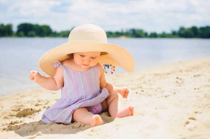 Kleine süße Mädchen am Strand mit großem Sonnenhut