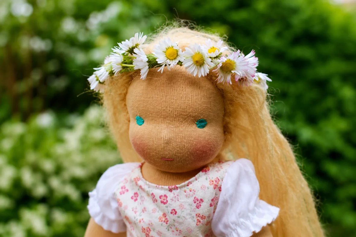 Puppe mit Blumenkranz auf dem Kopf