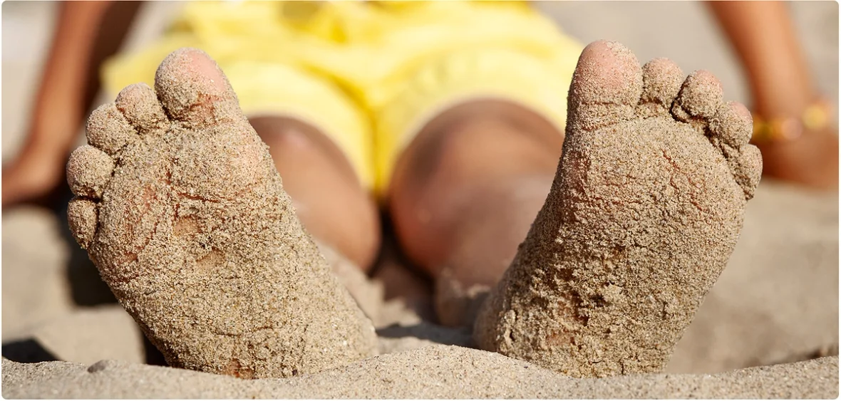 Barfuß am Strand, Sand klebt an den Füßen