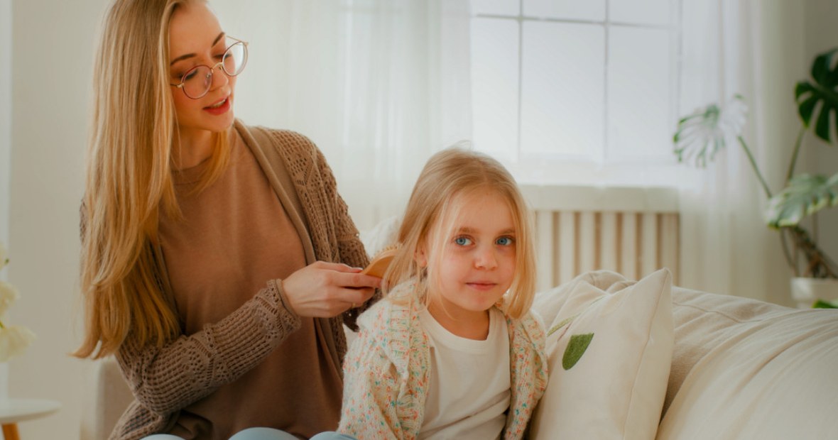 Mutter bürstet Mädchen ordentlich die Haare aus.