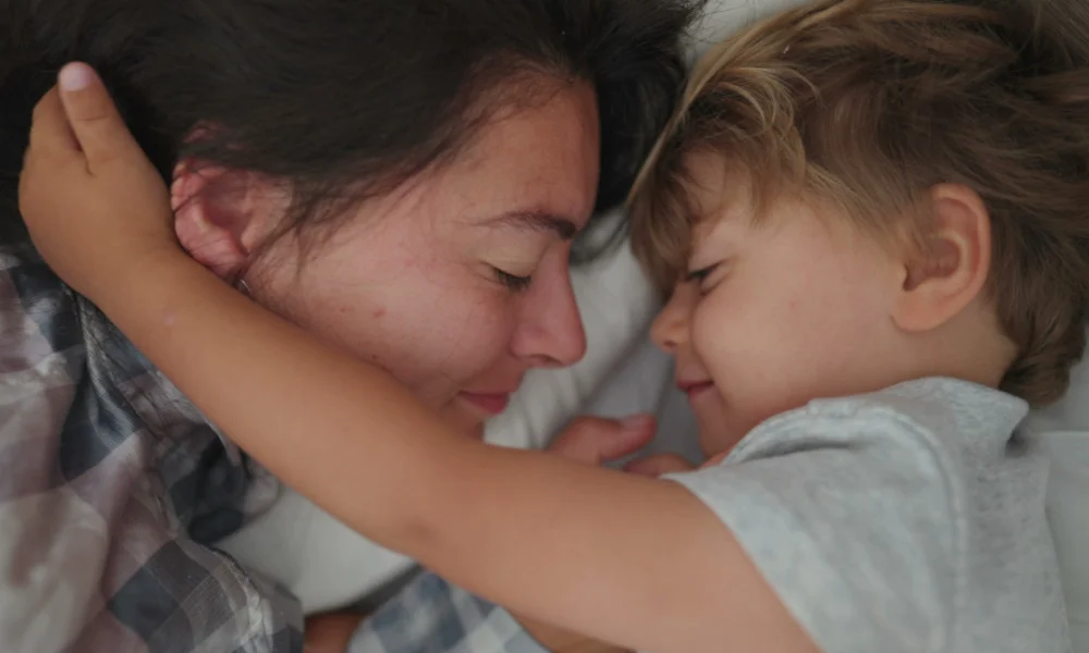 Mutter und Kind liegen im Bett und sehen sich liebevoll an.