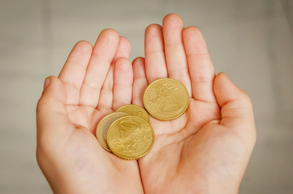Kinderhände - auf den Handflächen liegt Münzgeld