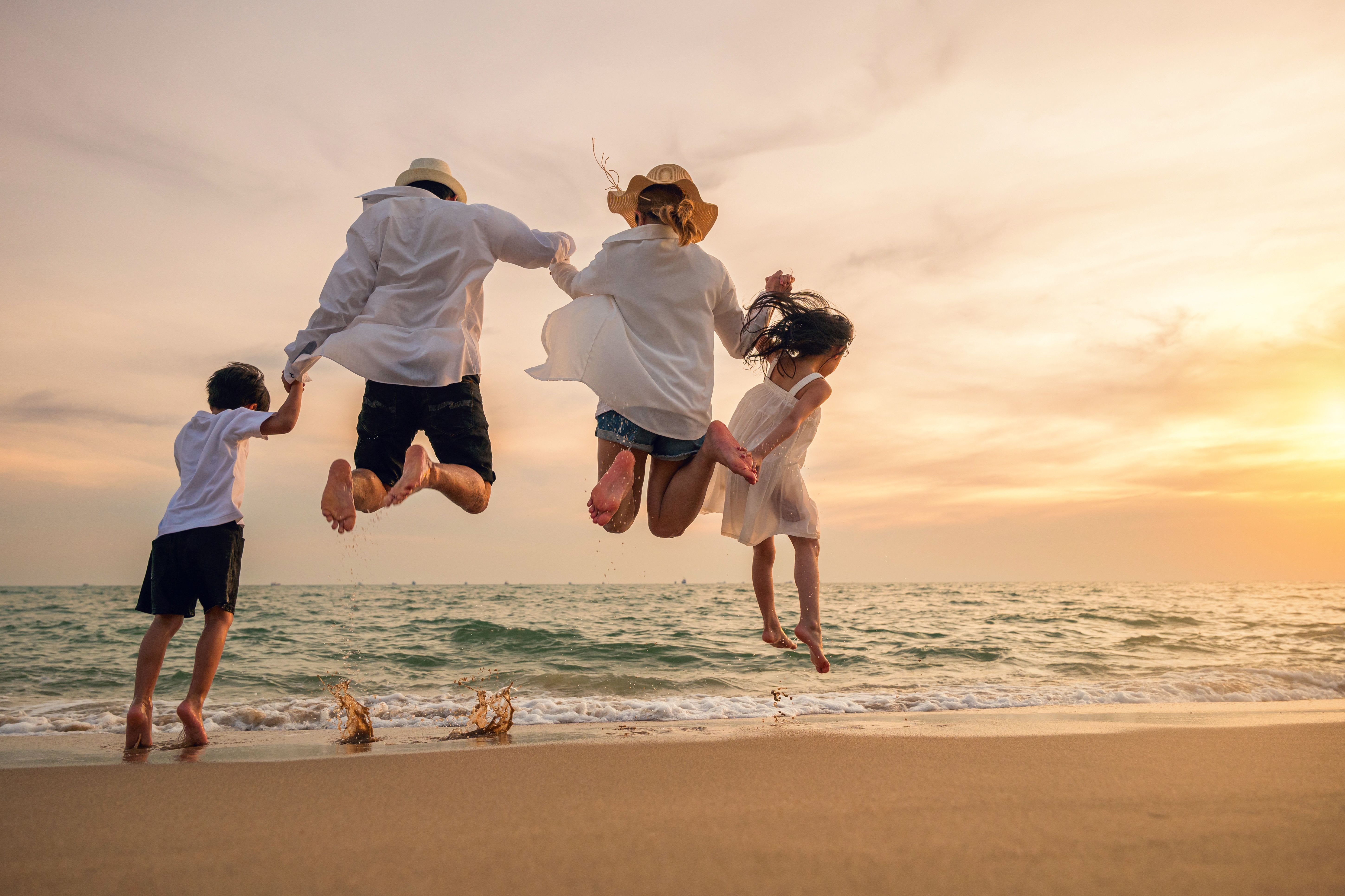 Happy family have fun jumping on beach in holiday at sunset