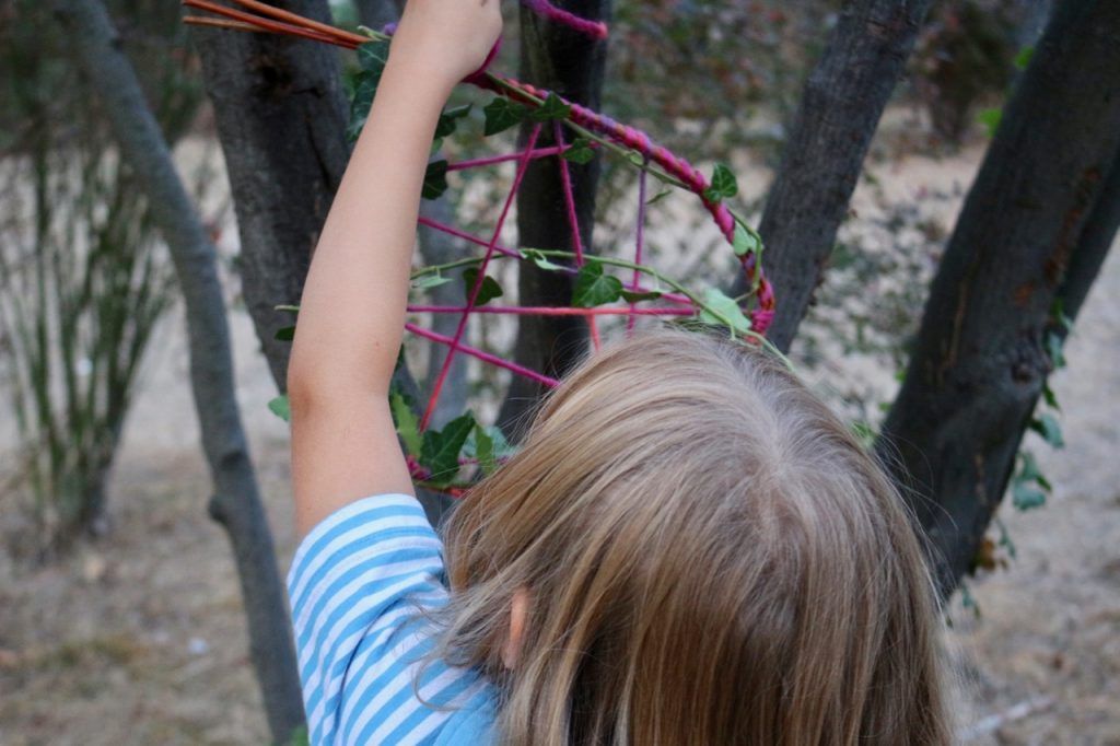 Kind hängt am Baum Traumfänger auf.