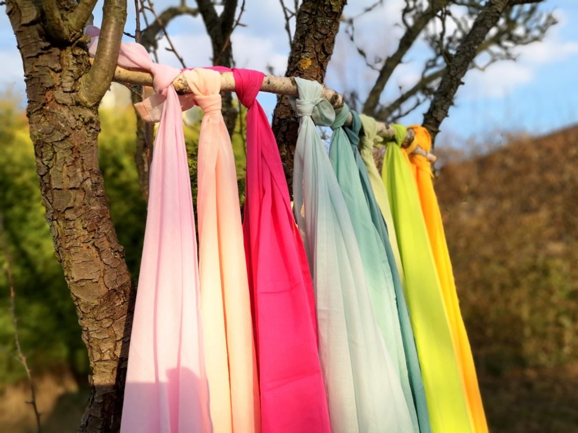 Pastellfarbene Spieltücher hängen in harmonischen Farben am Baum