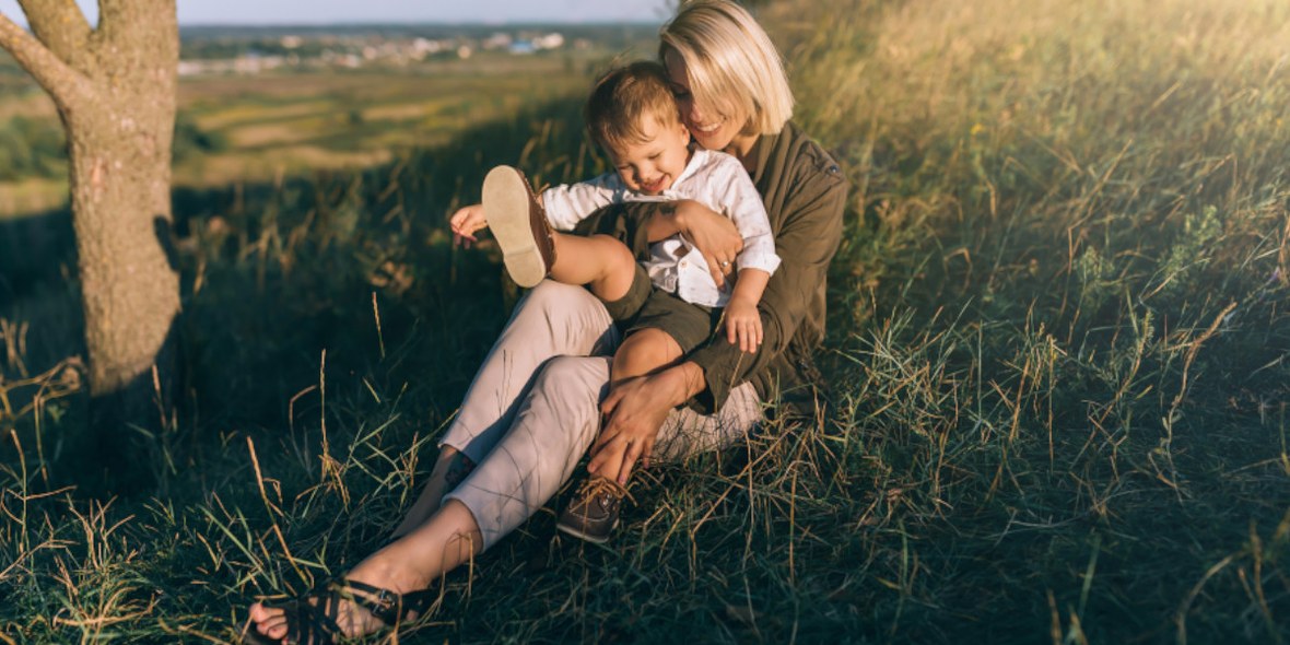 Mutter und Kind sitzen im Gras und genießen die Natur