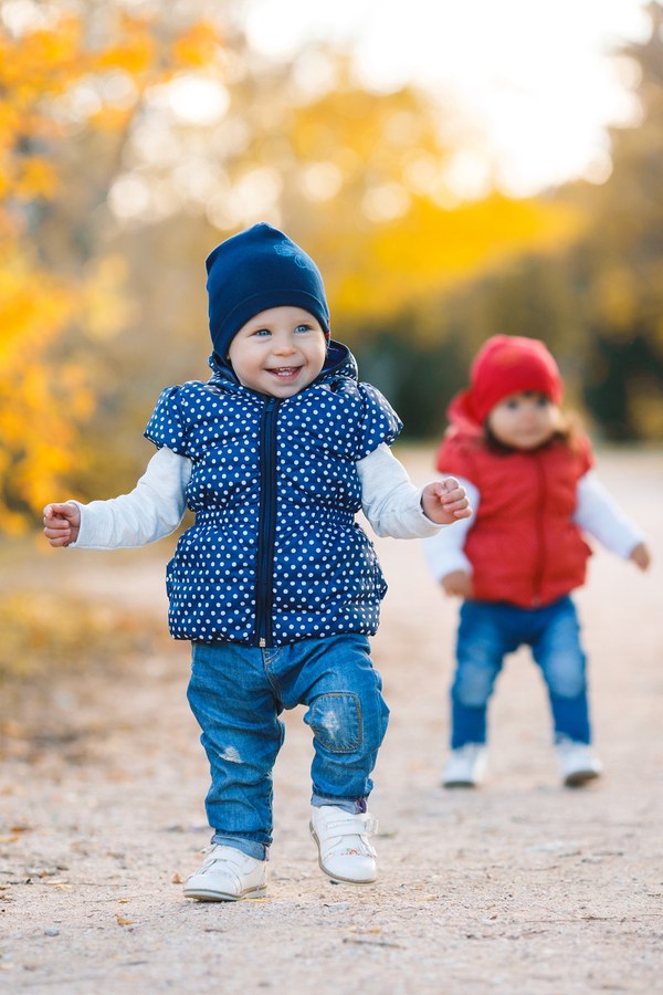 Kleinkinder machen draußen ihre ersten Schritte in Kinderschuhen.