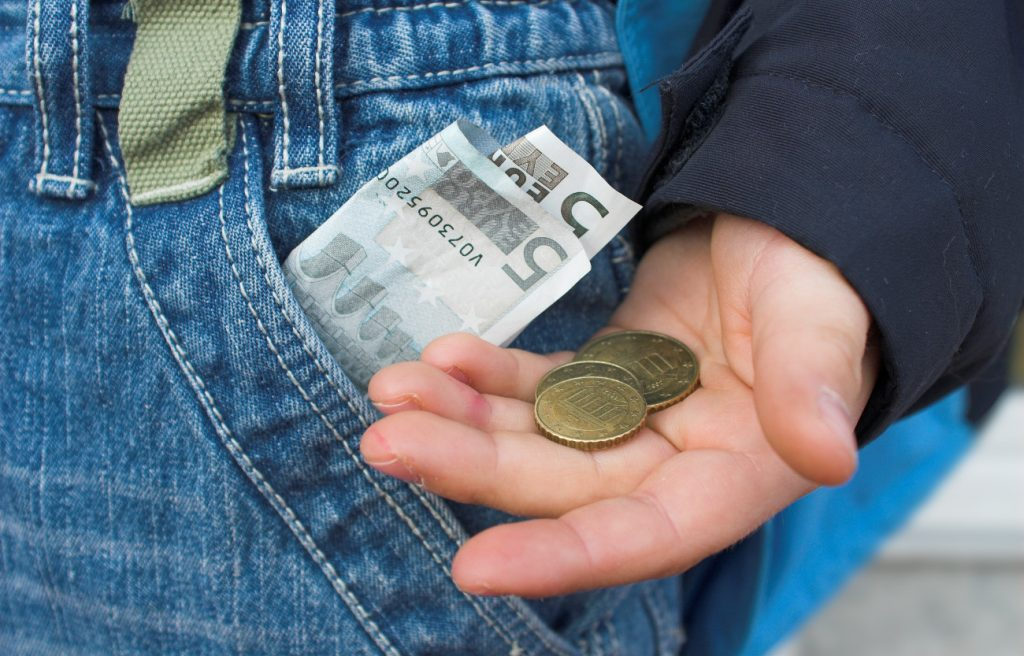In Kinderhand Münzgeld und in der Kinderhose eine Euronote