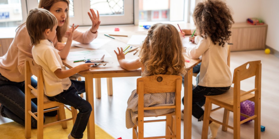 Kindergärtnerin am Tisch mit Kindergartenkindern
