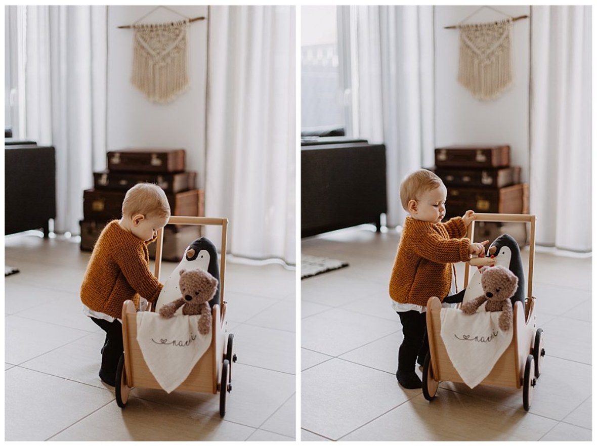 Kleinkind spielt mit Kuscheltieren und Holzpuppenwagen