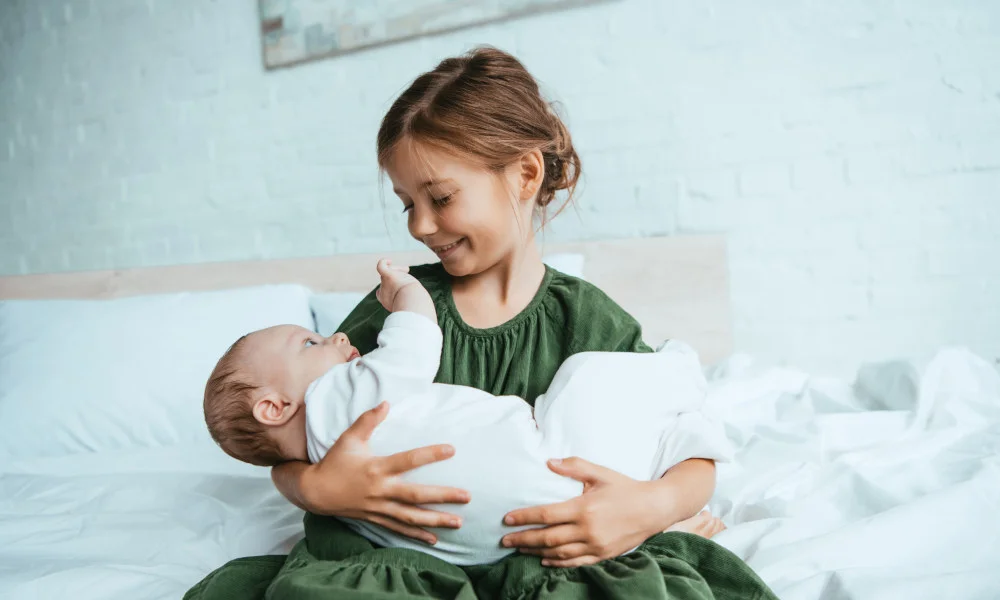 Mädchen hält Baby im Arm