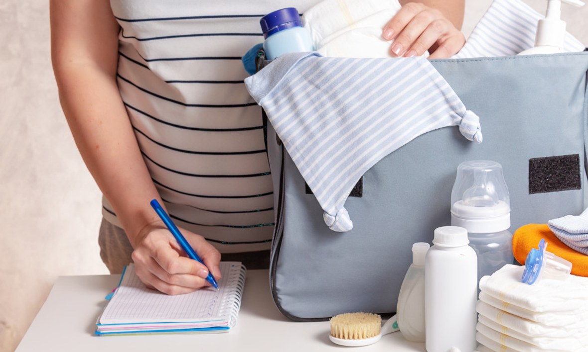 Mutter packt Wickeltasche mit Babyausstattung 