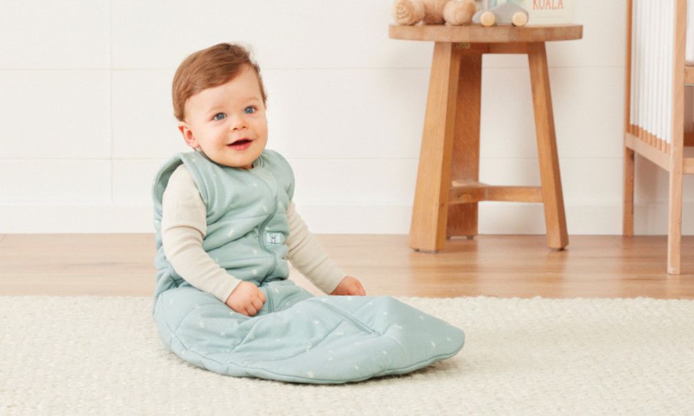 Glückliches Baby sitzend im Schlafsack