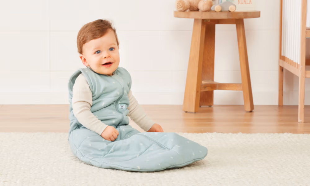 Glückliches Baby sitzend im Schlafsack