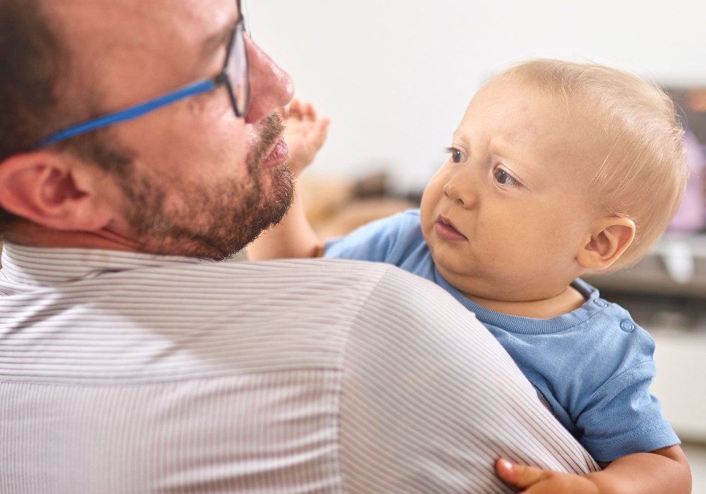 Baby fühlt sich unwohl auf dem Arm eines Mannes und fremdelt