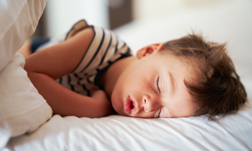 Junge schläft entspannt im Bett.