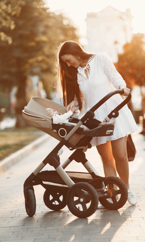 Glückliche Frau beugt sich über ihr Baby im Kinderwagen