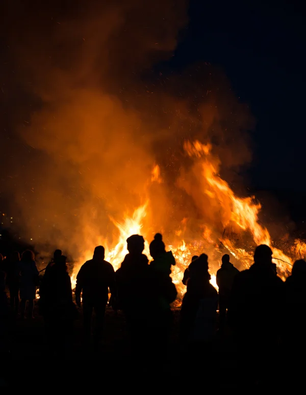 Osterfeuer brennt hell in der Nacht. Es ist umgeben von dunklen Silhouetten.
