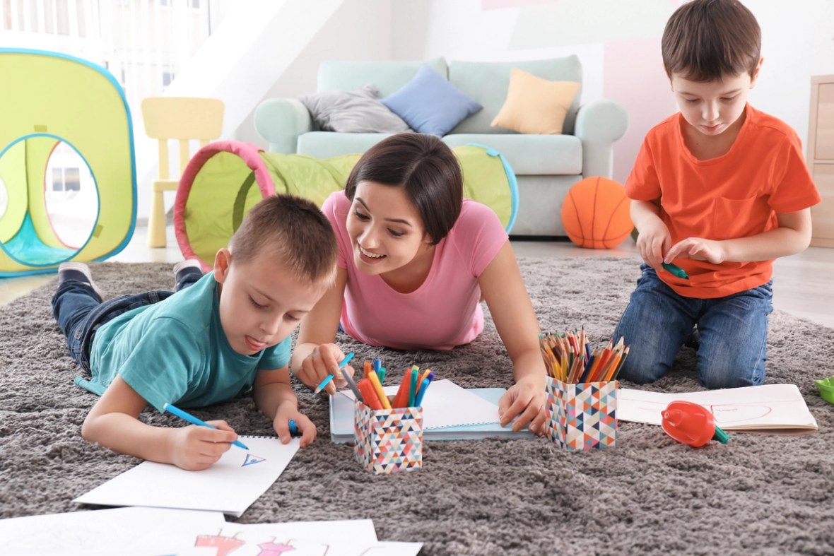 Kleine Jungen zeichnen mit Kindermädchen 