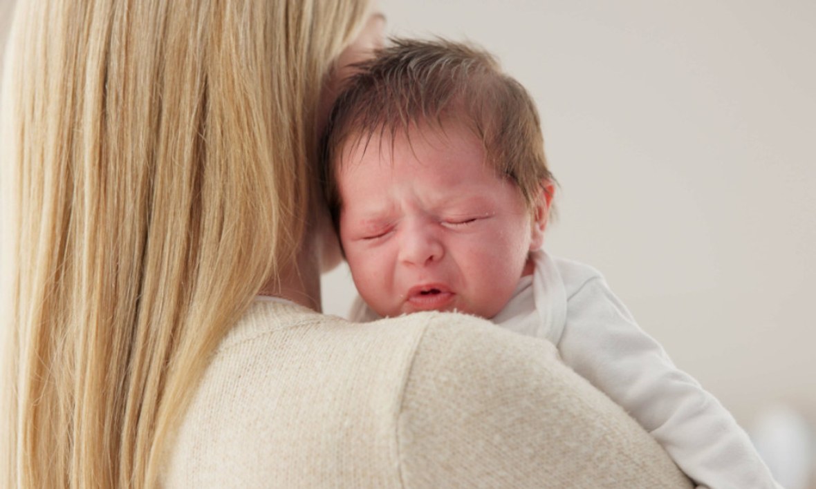 Mütter tröstet Baby auf dem Arm.