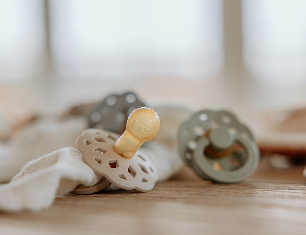 Schnuller von BIBS liegen auf Holz. Das Bild ist in Sanften Tönen gestaltet.