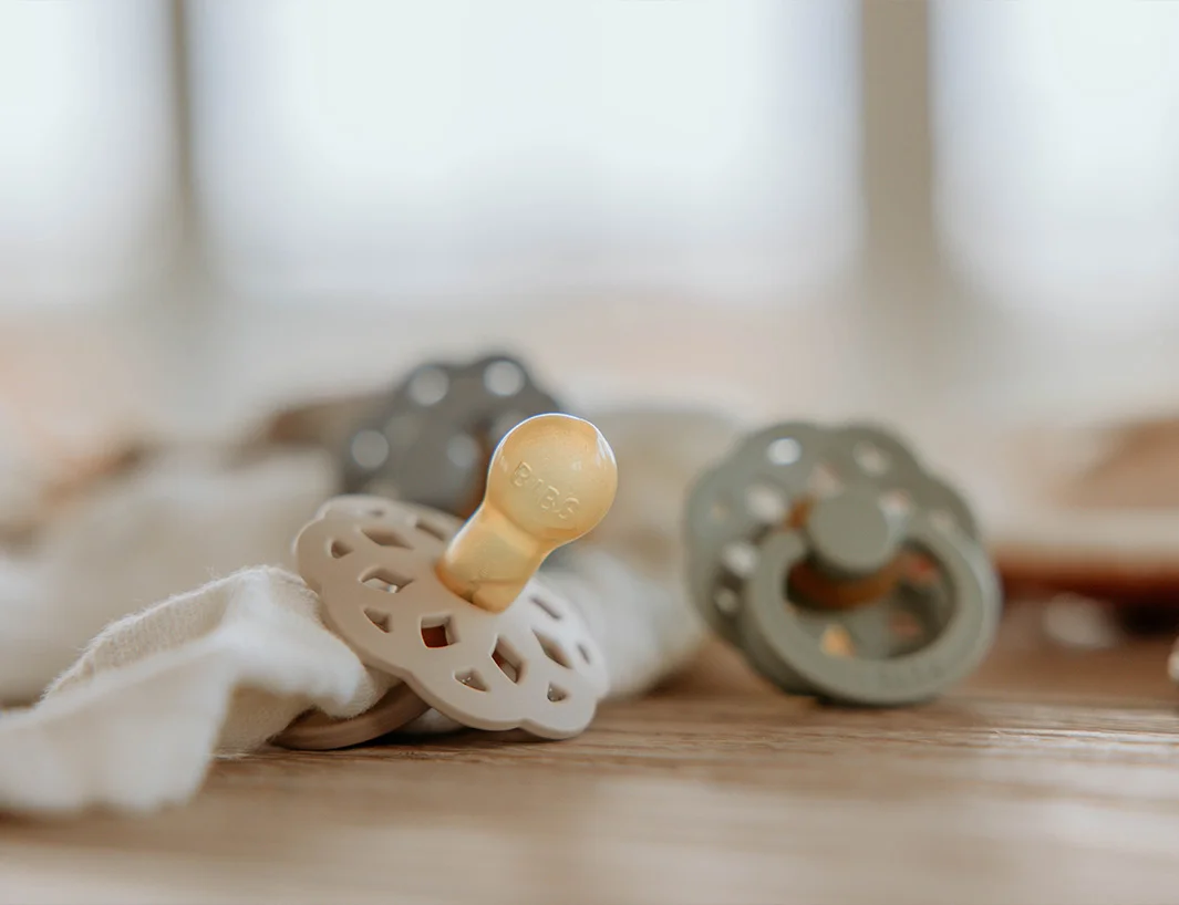 Schnuller von BIBS liegen auf Holz. Das Bild ist in Sanften Tönen gestaltet.