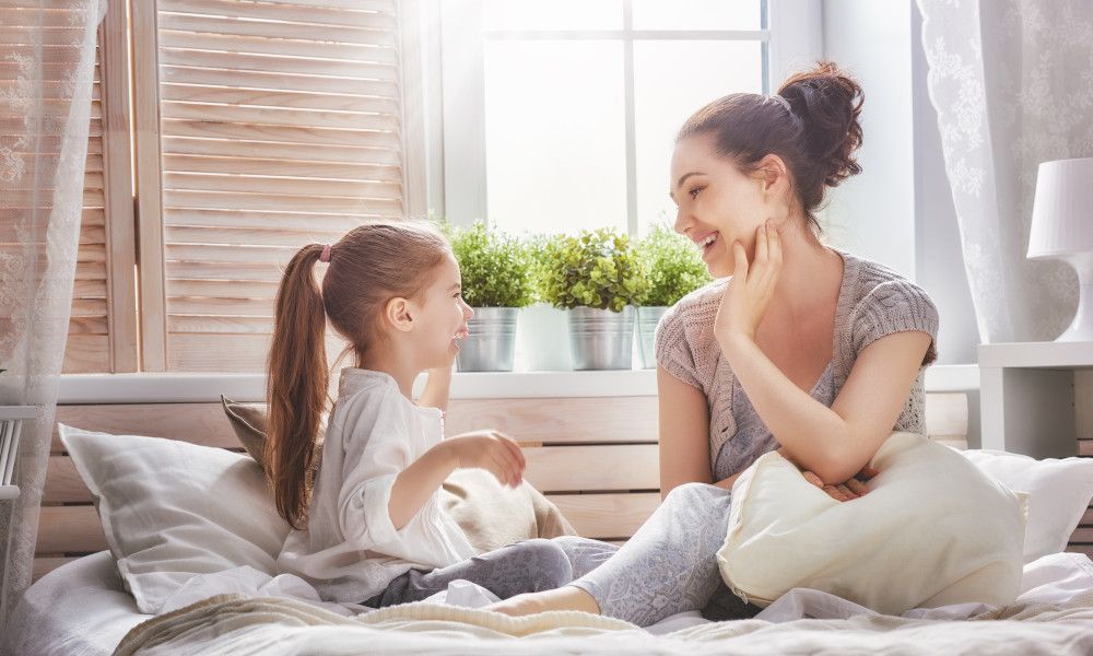 Mutter und Kind sitzen auf einem Bett und unterhalten sich