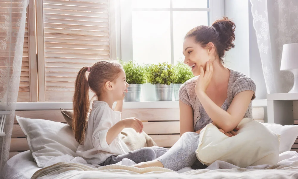 Mutter und Kind sitzen auf einem Bett und unterhalten sich