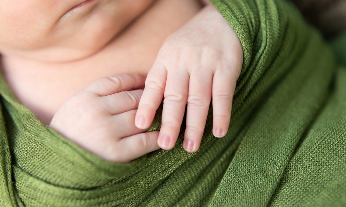 Gepucktes Baby in einem grünen Pucktuch.