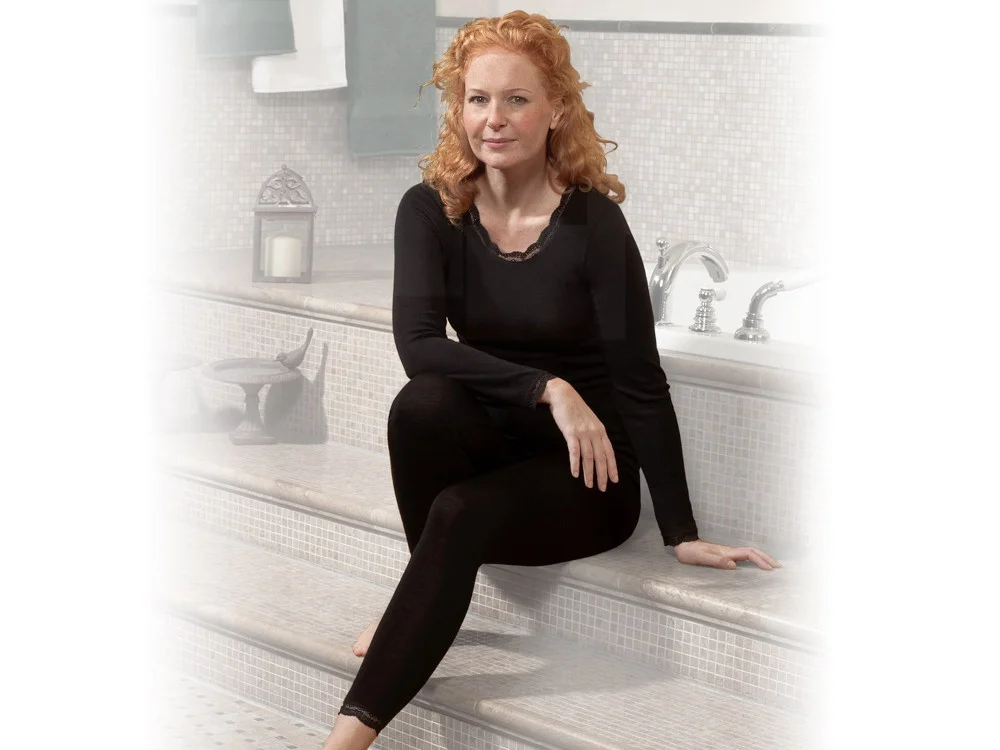 Frau sitzt mit Langarmunterhemd und Leggings da.