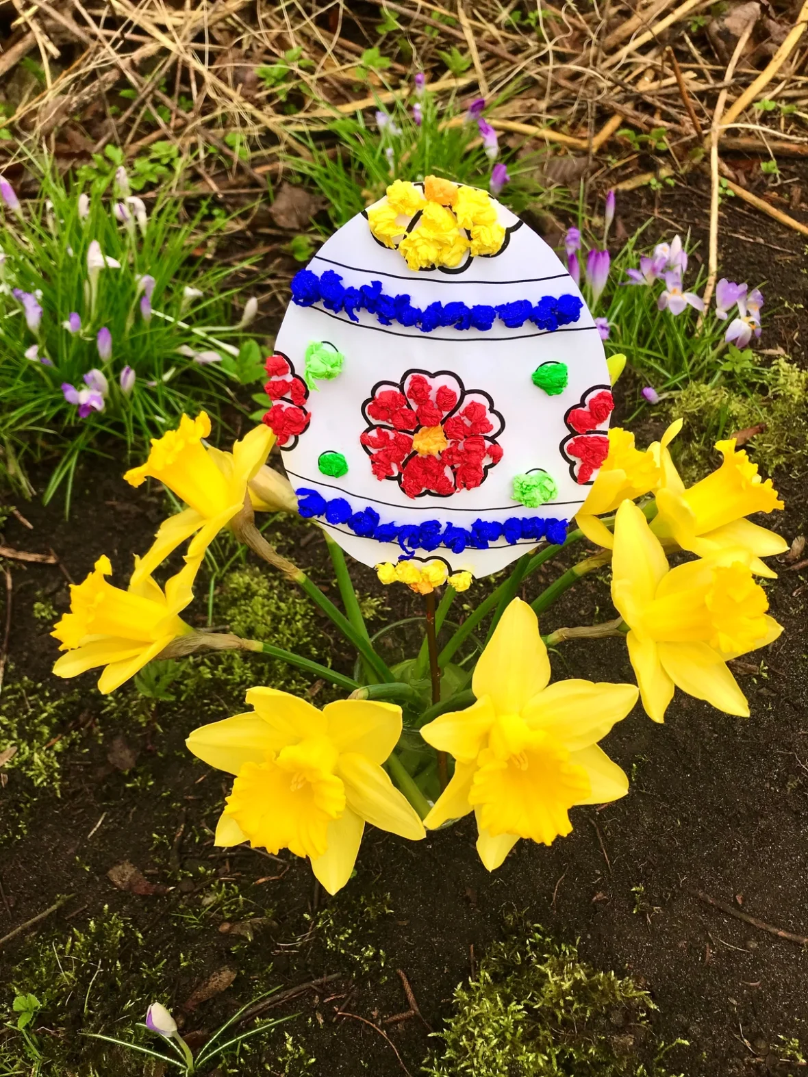 Oster-Knüddelchen-Ei als Beispiel im Garten umgeben von gelb leuchtenden Osterglocken