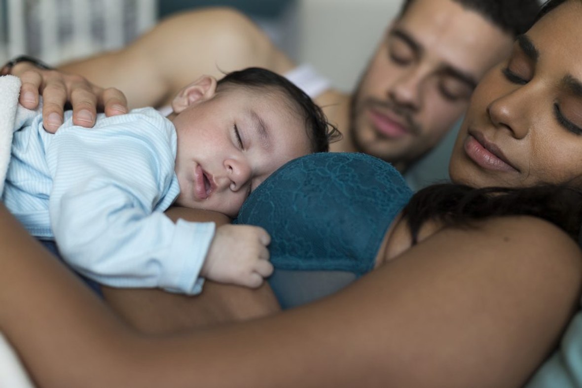 Entspannte Eltern und Baby schlafen im Bett