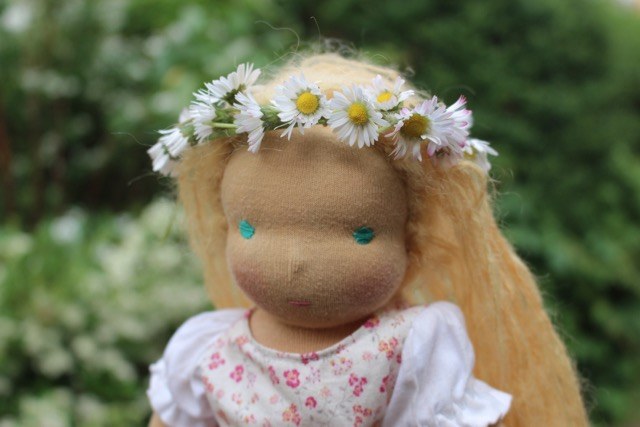Puppe mit Blumenkranz auf dem Kopf