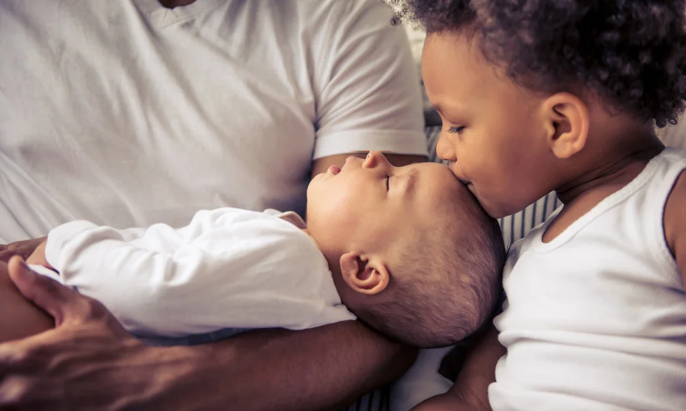 Kleiner Junge küsst Baby auf den Kopf
