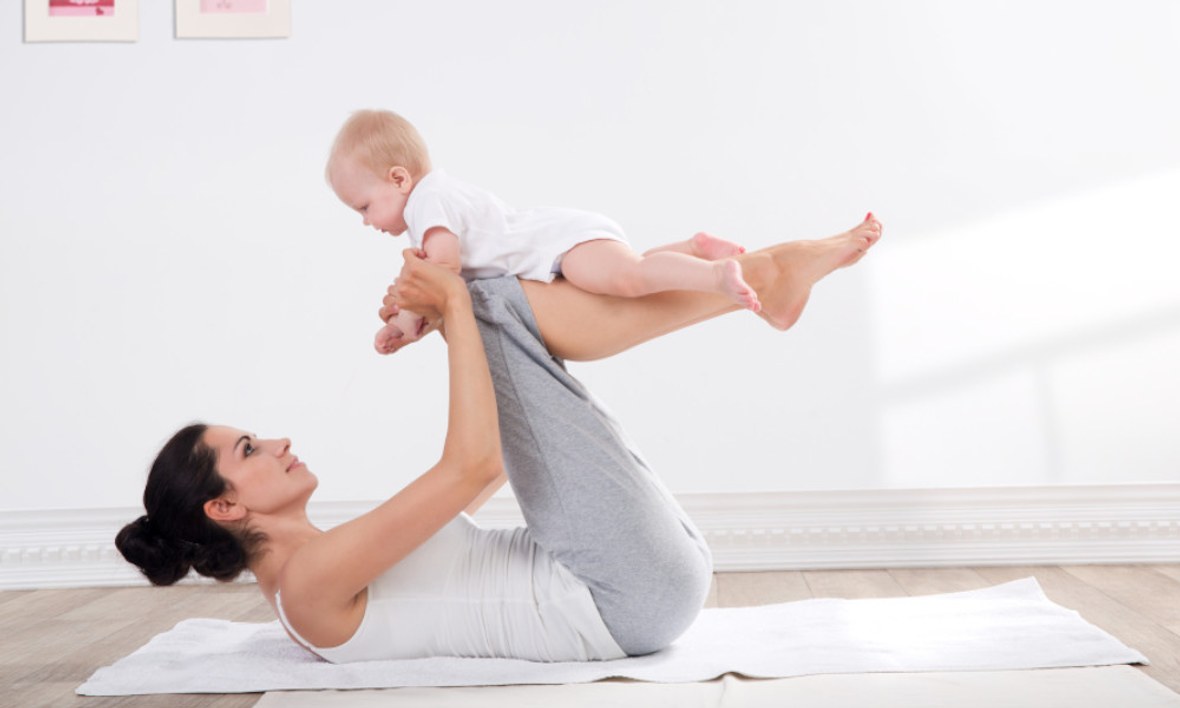 Frau macht mit Baby Beckenbodentraining